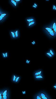 many blue butterflies are flying in the dark, with one light on them's wings