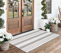 the front door is decorated with wreaths and potted plants on the porch area