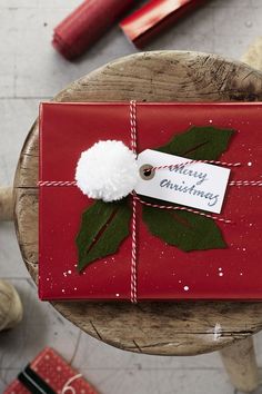 a present wrapped in red and green paper with a white pom - pom on it