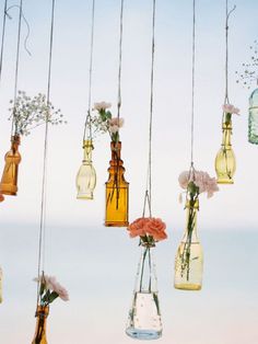 hanging glass bottles with flowers in them are suspended from the ceiling by strings and string