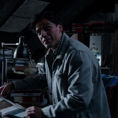 a man standing in front of a desk holding a book