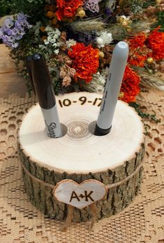 two knives sitting on top of a piece of wood with flowers in the back ground