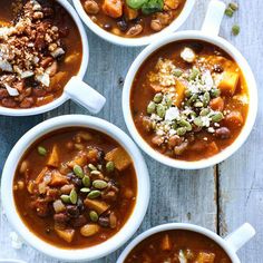 four white bowls filled with soup on top of a wooden table