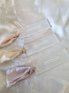 three pieces of cloth with the names hannah and hannah written on them sitting on a white sheet