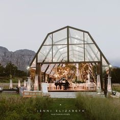 an outdoor wedding venue set up in the middle of a field with mountains in the background