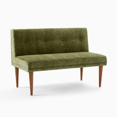 a green couch sitting on top of a white floor next to a wooden leg chair