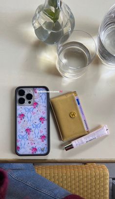 a cell phone case sitting on top of a table next to a wallet and water