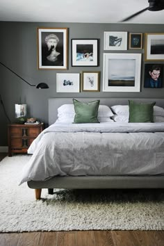 a bedroom with grey walls and pictures on the wall above the bed in front of it