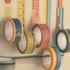 several rolls of tape hanging on a wall next to a measuring tape holder and ruler