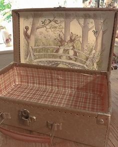 an old suitcase is sitting on the floor in front of a window with snow covered trees