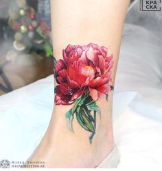 a woman's foot with a flower tattoo on the side of her leg,