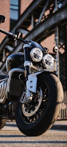 the motorcycle is parked on the side of the road near a building with an overpass