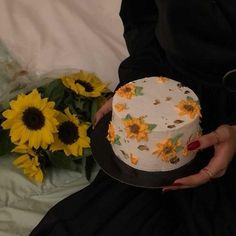 a woman holding a cake with sunflowers on it