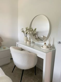 a white chair sitting in front of a desk with a mirror on top of it