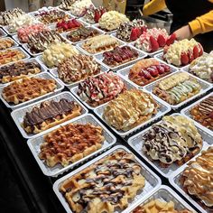 many different types of waffles and other desserts on display in trays