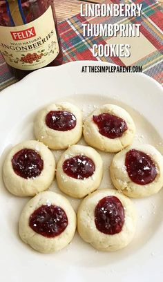 cookies with jam are on a plate next to a bottle of wine