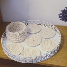 crocheted baskets and coasters on a white platter sitting on a wooden table