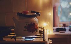 a tea pot sitting on top of a stove in front of a window with candles