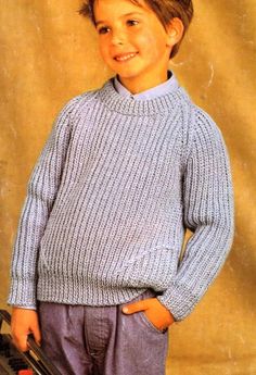 a young boy is wearing a blue sweater and pants with his hands in his pockets