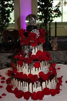 a three tiered wedding cake decorated with red roses and chocolate drizzles