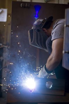 welder working on the back of a piece of metal with sparks coming from it