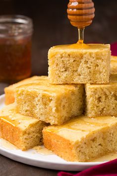 a white plate topped with slices of cake next to a jar of honey on the table