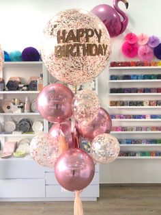 a bunch of balloons that say happy birthday with flamingos in the background and confetti all around them