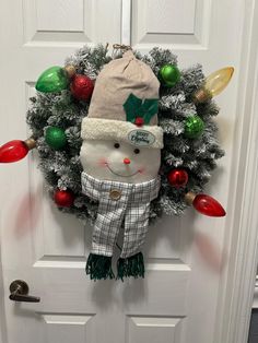 a christmas wreath with a snowman wearing a hat and scarf hanging on the front door