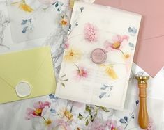 an assortment of stationery and envelopes laid out on a floral print tablecloth