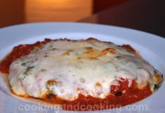 a white plate topped with lasagna covered in sauce