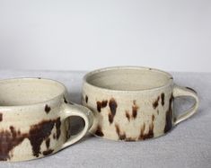 two brown and white coffee mugs sitting next to each other