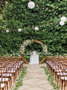 an outdoor ceremony setup with white linens and paper lanterns hanging from the ceiling, surrounded by greenery