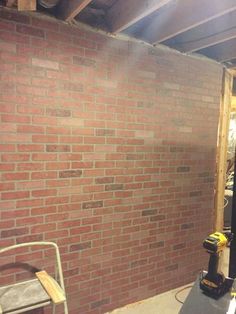 an unfinished room with brick walls and tools in the foreground, including a work bench