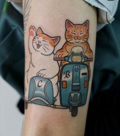 two cats sitting on the back of a scooter with another cat behind it