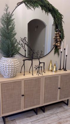 a mirror sitting on top of a wooden dresser next to a christmas tree and other decorations