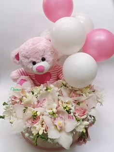 a teddy bear with balloons and flowers in a vase