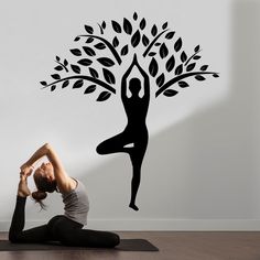 a woman doing yoga in front of a tree wall decal