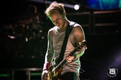 a man playing guitar on stage at a concert