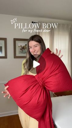 a woman holding a large red pillow in her hands with the words pillow bow for my front door