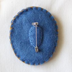 a blue felt brooch with a metal pin on it