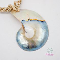 a white and blue shell with some beads on it's end, next to a bead necklace