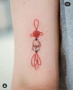 a small tattoo on the arm of a woman with a red ribbon around her neck