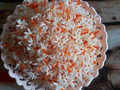 a bowl filled with white and orange flowers on top of a wooden table