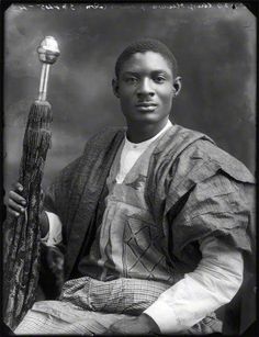 an old black and white photo of a young man holding a stick in his hand