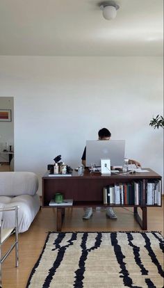 a person sitting at a desk in front of a laptop computer on top of a wooden table