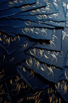 a pile of blue and gold foiled business cards with golden lettering on the edges