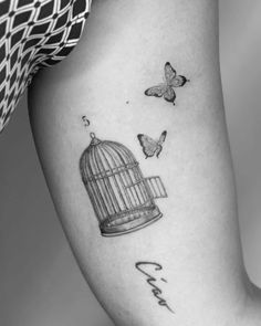 a woman's thigh with a birdcage and butterflies on it