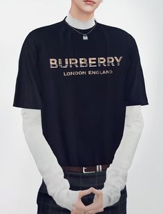 a man wearing a black shirt with white sleeves and the words burberry printed on it