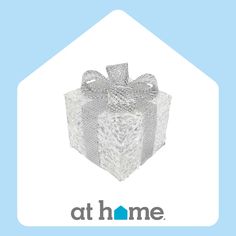 a white gift box with a bow on the top and at home logo below it