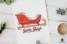 a santa sleigh christmas card on top of a table next to a cup of coffee